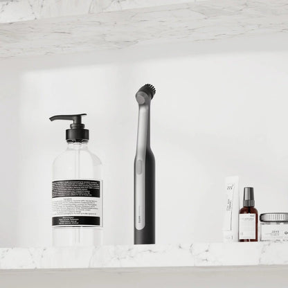 Close-up angle of the white HOTO Wand Cordless Spin Scrubber with magnetic brush head attached in a modern tiled bathroom setting.
