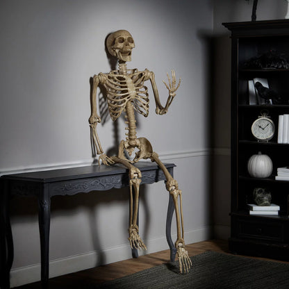 Full-length front view of a realistic 7ft natural bone-colored poseable skeleton standing against an indoor neutral wall.