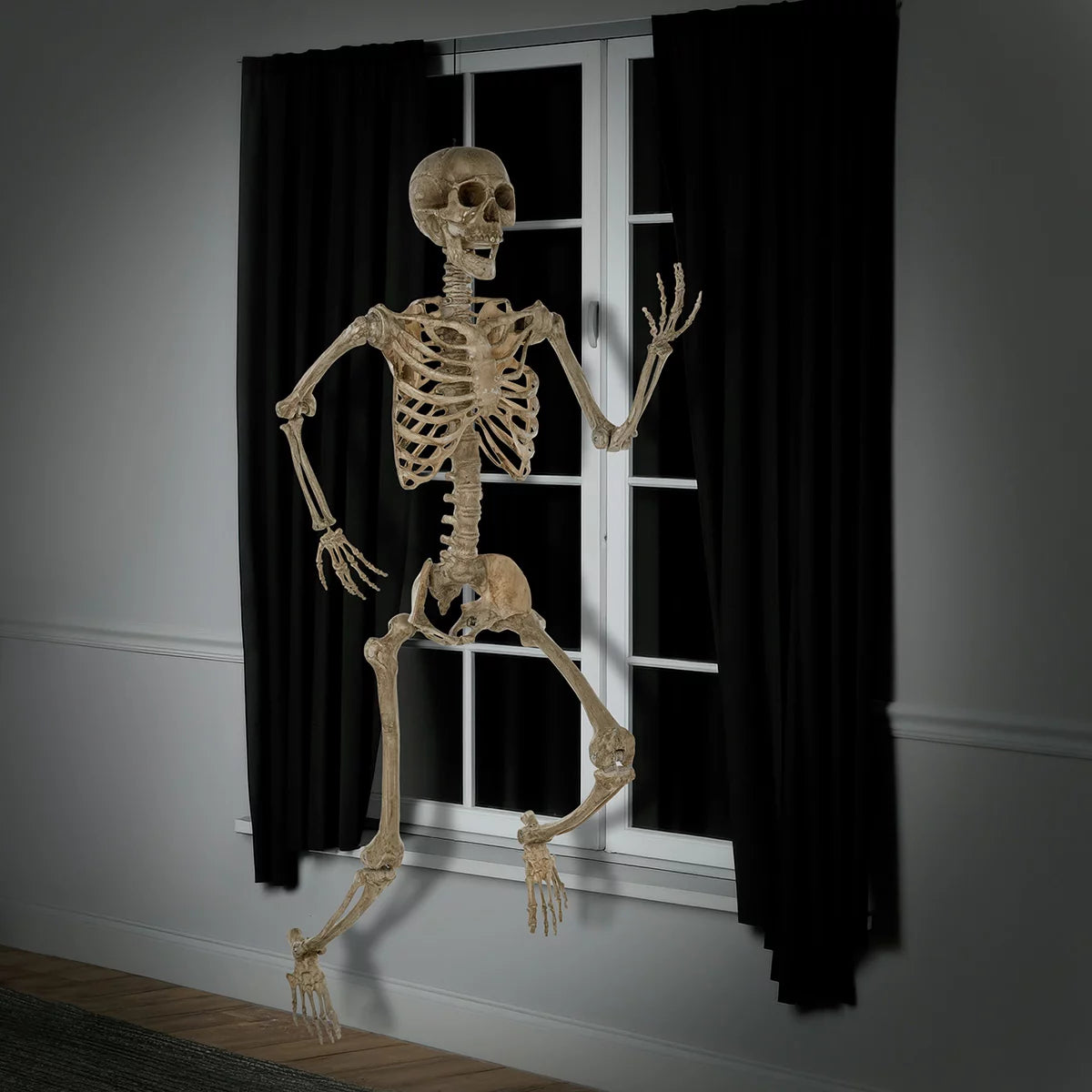 Full-length front view of a realistic 7ft natural bone-colored poseable skeleton standing against an indoor neutral wall.