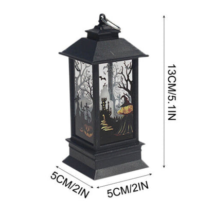 A black Gothic Halloween lantern featuring pumpkin and bat cutout designs, glowing with a warm flickering light on a dark wooden table.
