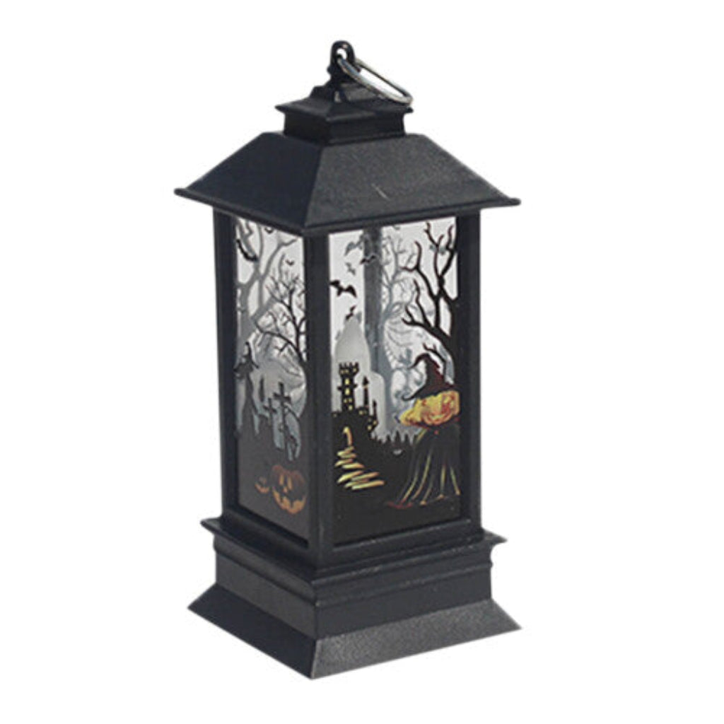 A black Gothic Halloween lantern featuring pumpkin and bat cutout designs, glowing with a warm flickering light on a dark wooden table.