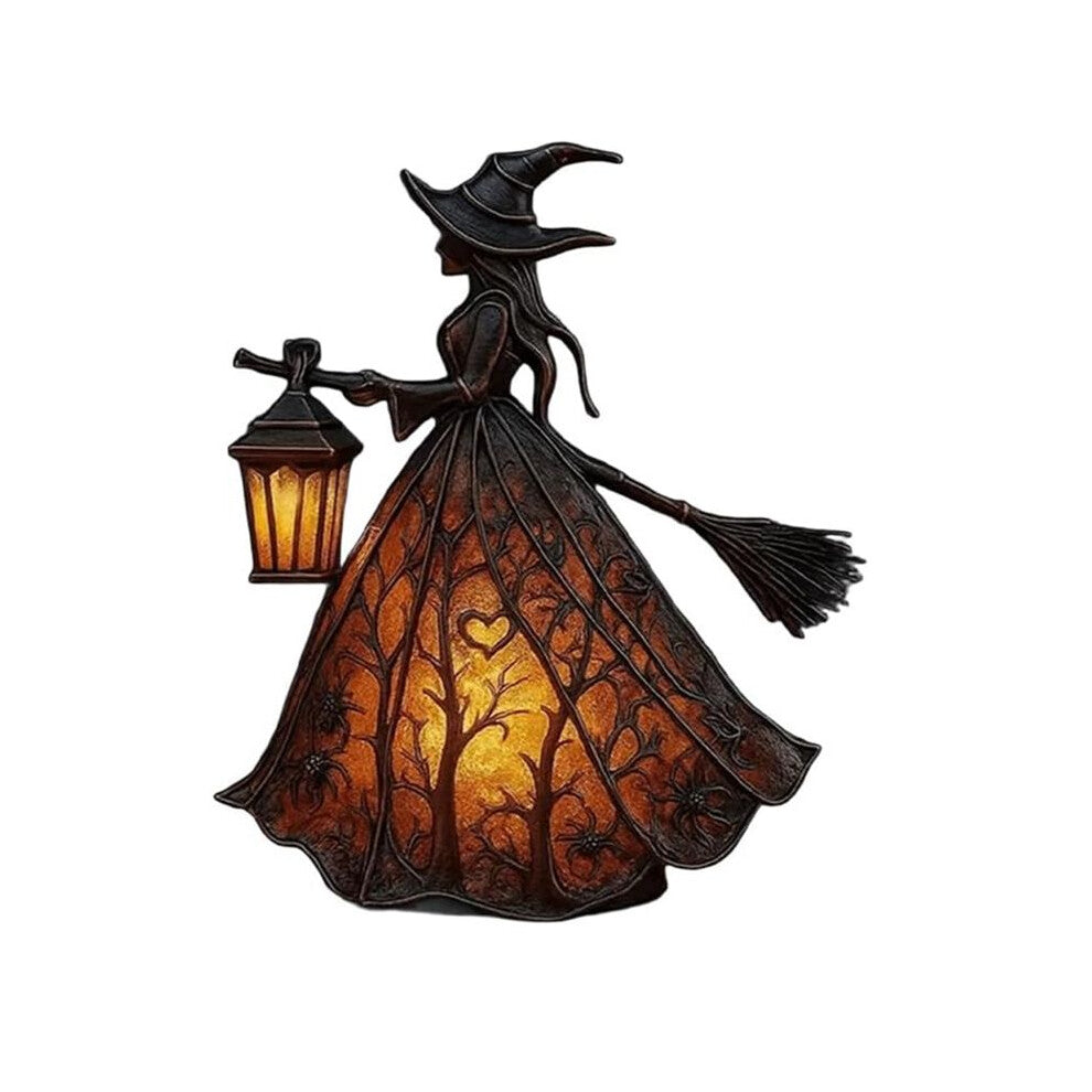 A detailed black resin Halloween gothic witch table lamp holding a glowing lantern on a dark wooden surface.