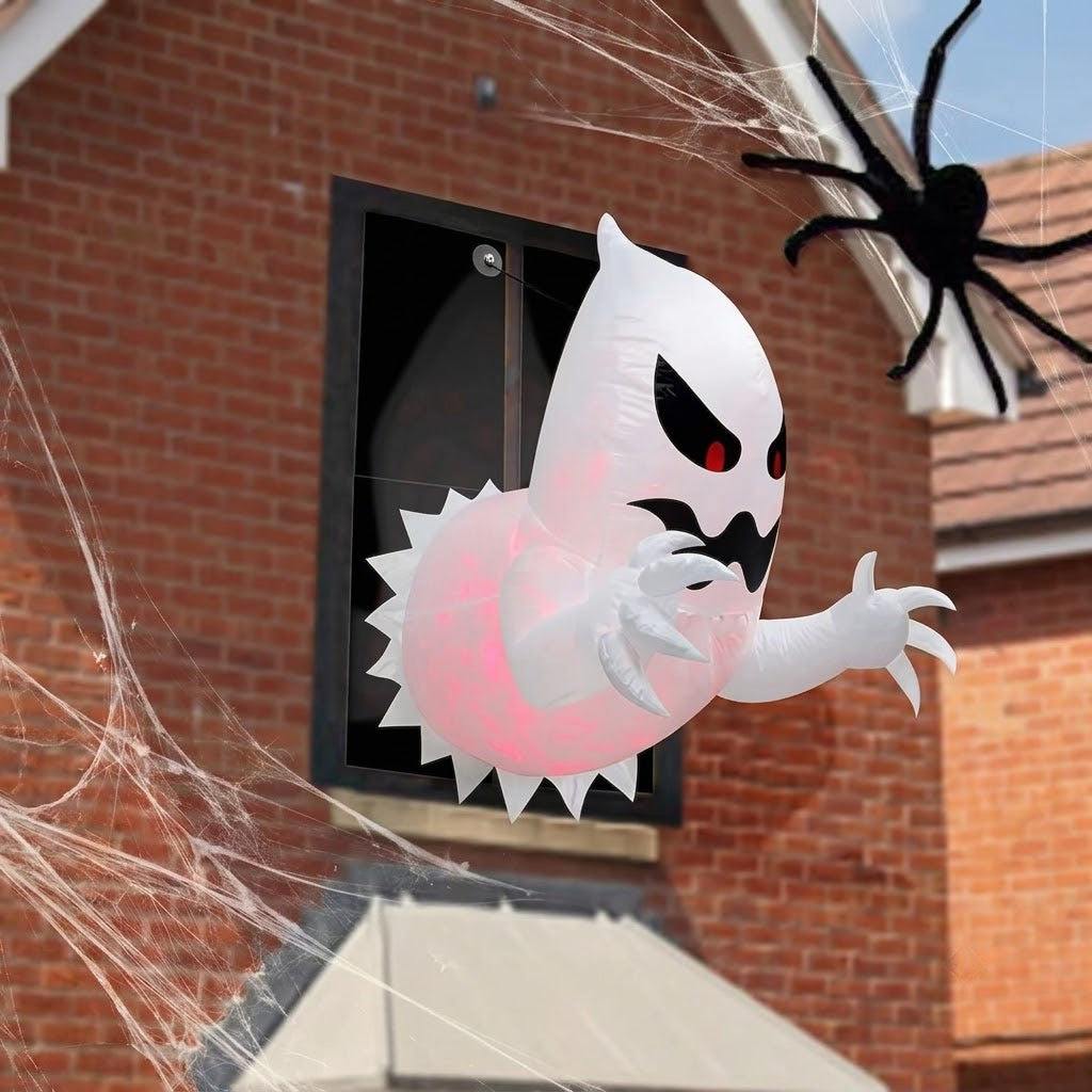 White polyester 4.6-foot inflatable Halloween ghost with internal red LED light bursting out of a house window frame at night.