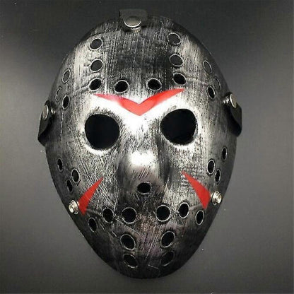 Front view of an iconic white and red painted Jason Voorhees Friday the 13th scary hollow out plastic mask on a dark background.