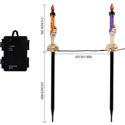 A 5-pack of Halloween lighted skeleton hand candle stakes glowing with warm white LEDs along a spooky outdoor garden lawn
