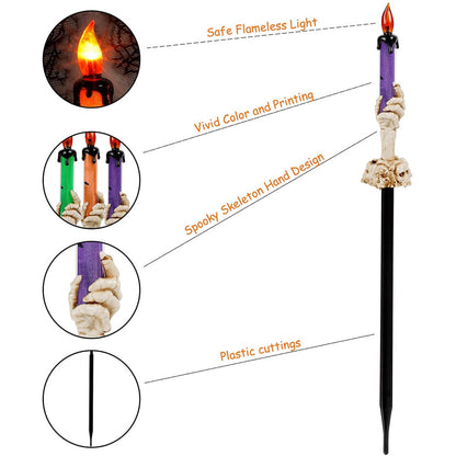 A 5-pack of Halloween lighted skeleton hand candle stakes glowing with warm white LEDs along a spooky outdoor garden lawn