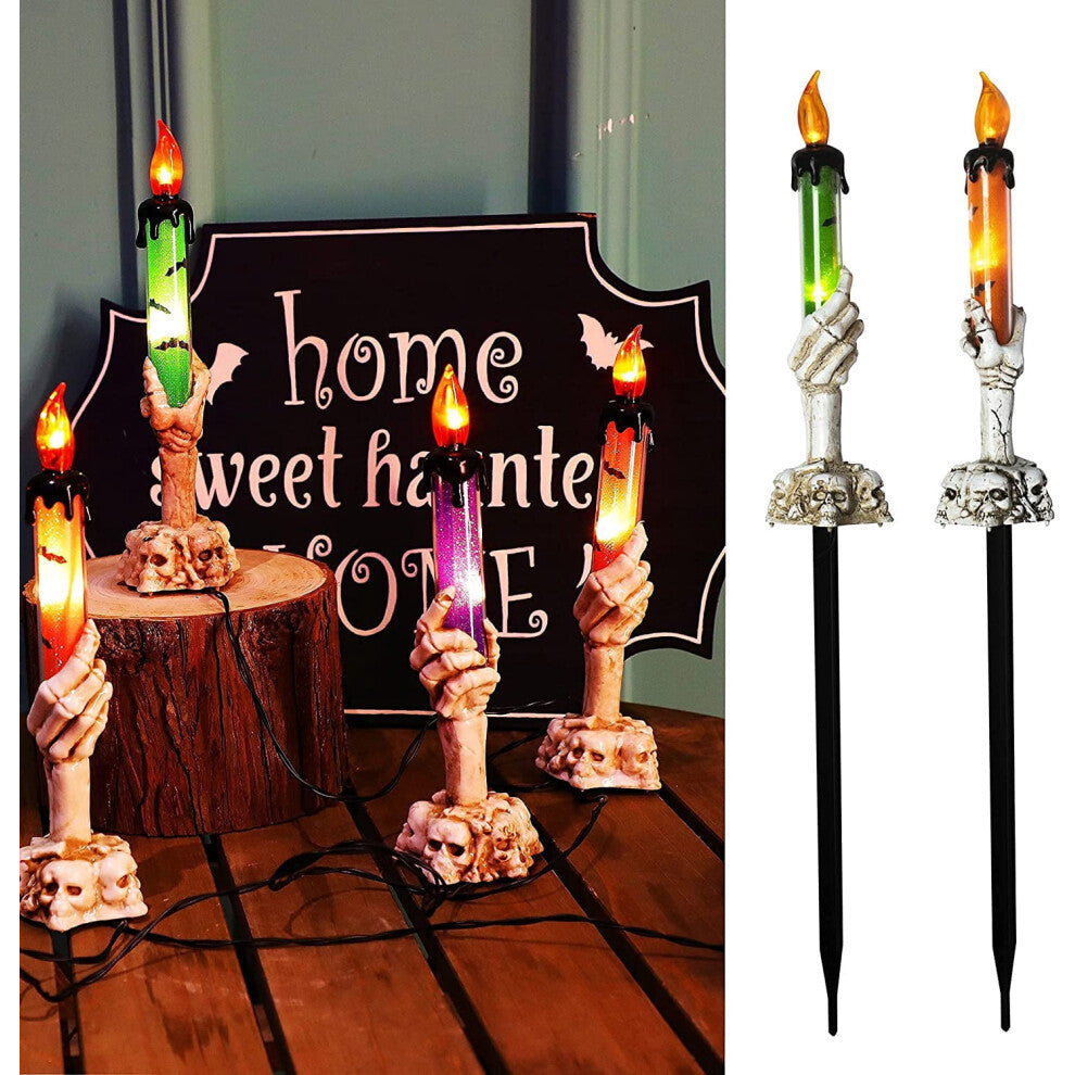 A 5-pack of Halloween lighted skeleton hand candle stakes glowing with warm white LEDs along a spooky outdoor garden lawn