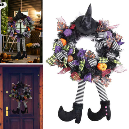 Black and orange Halloween witch door wreath with miniature broom, pointed hat, striped legs, and foam pumpkins hanging on a front door.