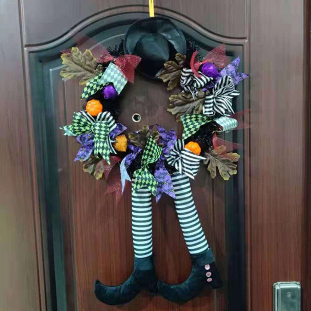 Black and orange Halloween witch door wreath with miniature broom, pointed hat, striped legs, and foam pumpkins hanging on a front door.