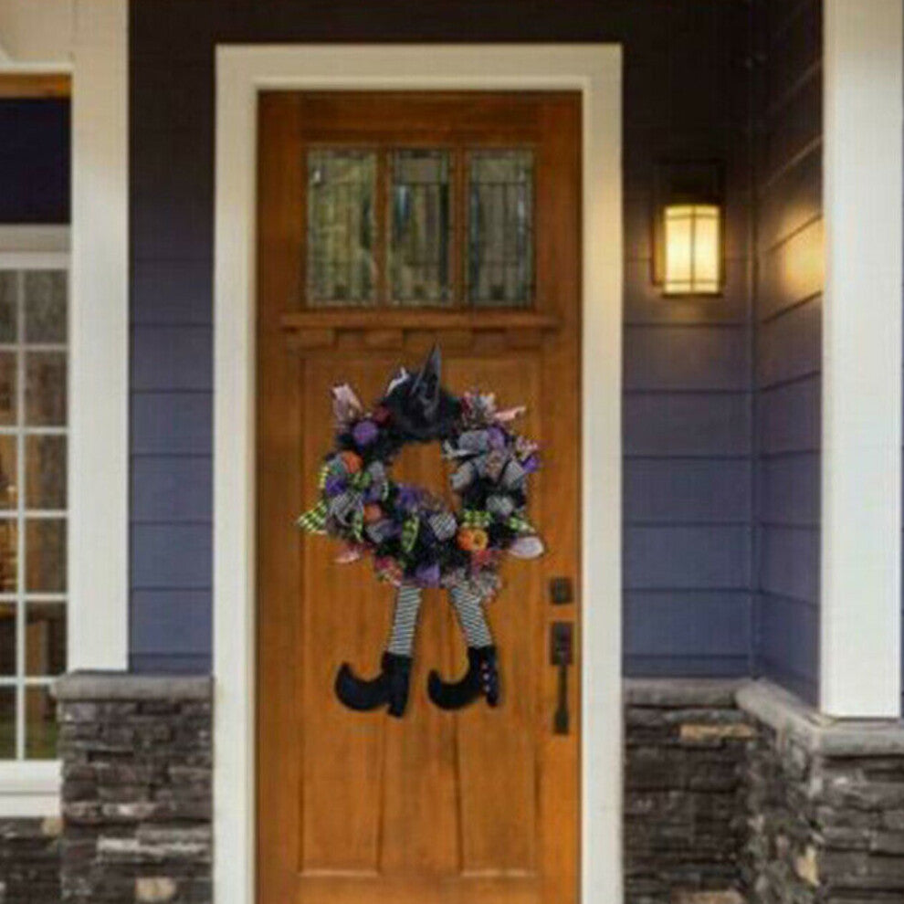 Black and orange Halloween witch door wreath with miniature broom, pointed hat, striped legs, and foam pumpkins hanging on a front door.