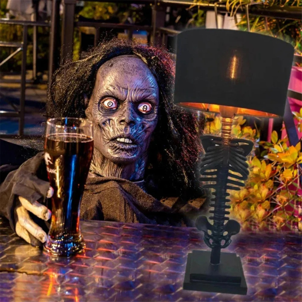 A Gothic resin skull desktop ambient light glowing on a dark workspace surface for Halloween party decoration.