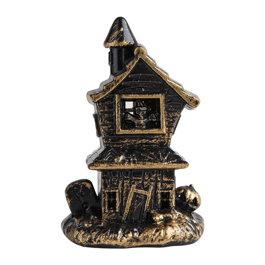 A miniature Halloween LED illuminated castle model glowing softly as part of a spooky village accessory set on a festive table.