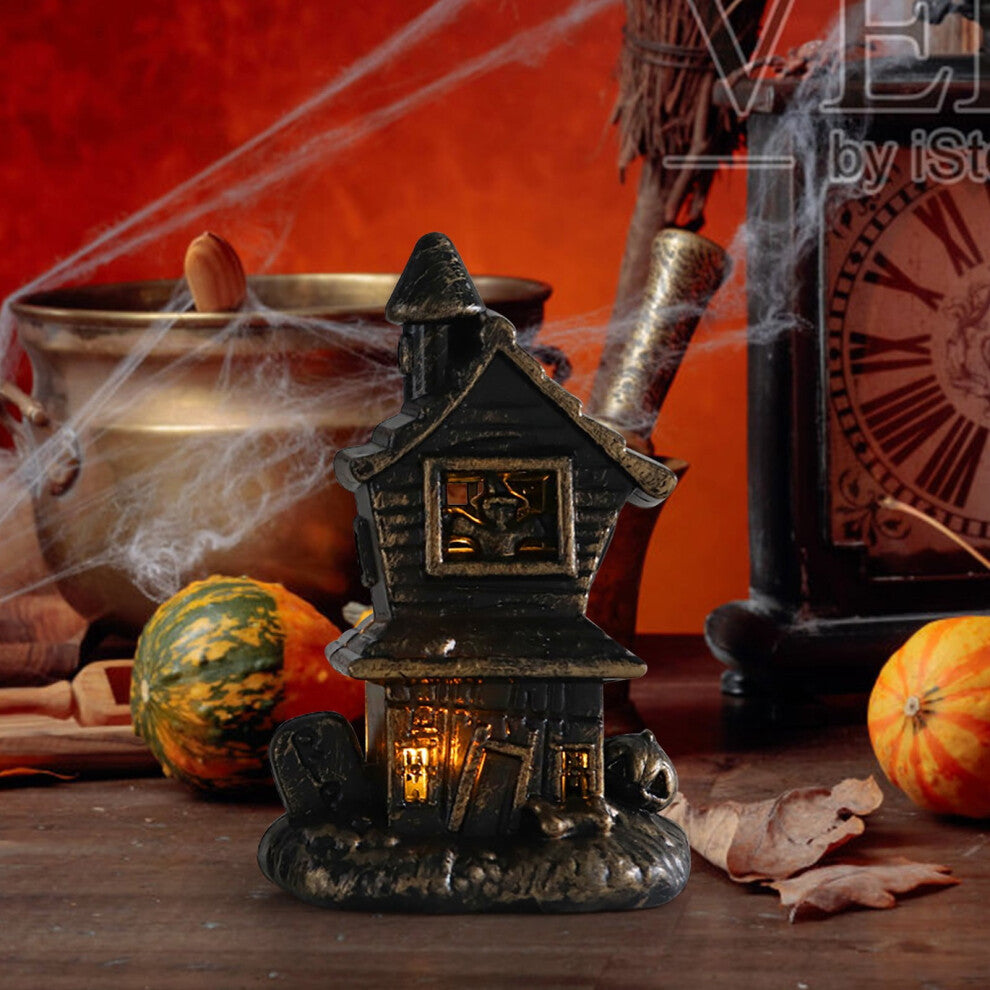 A miniature Halloween LED illuminated castle model glowing softly as part of a spooky village accessory set on a festive table.