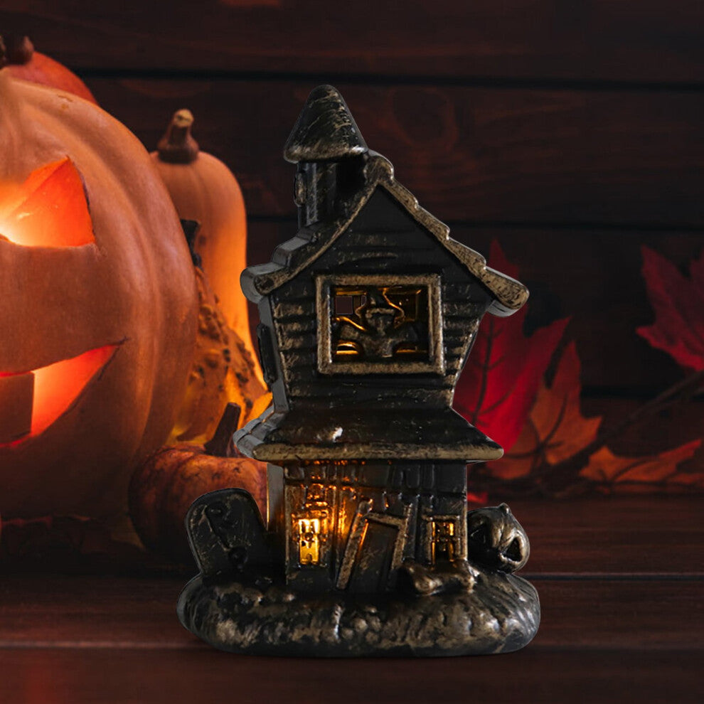 A miniature Halloween LED illuminated castle model glowing softly as part of a spooky village accessory set on a festive table.