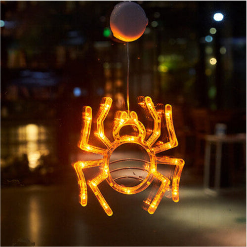 An illuminated Halloween window LED light with a suction cup glowing brightly against a glass pane at night.
