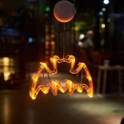 An illuminated Halloween window LED light with a suction cup glowing brightly against a glass pane at night.
