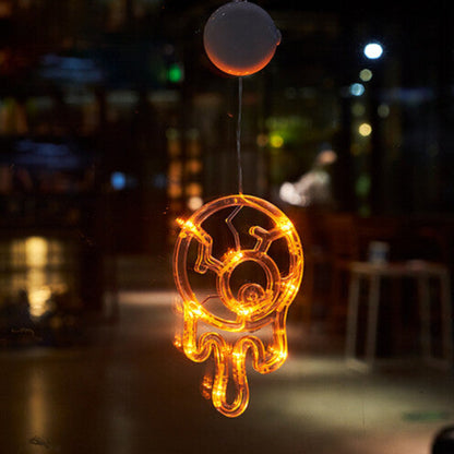 An illuminated Halloween window LED light with a suction cup glowing brightly against a glass pane at night.