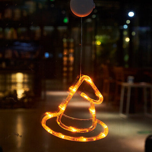An illuminated Halloween window LED light with a suction cup glowing brightly against a glass pane at night.