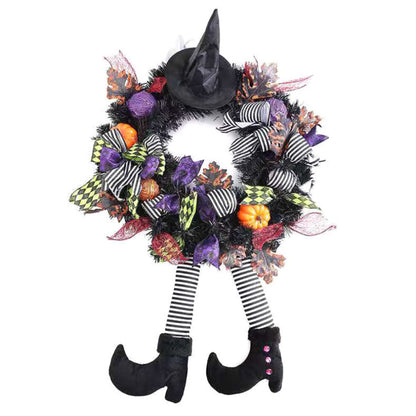 Black and orange Halloween witch door wreath with miniature broom, pointed hat, striped legs, and foam pumpkins hanging on a front door.