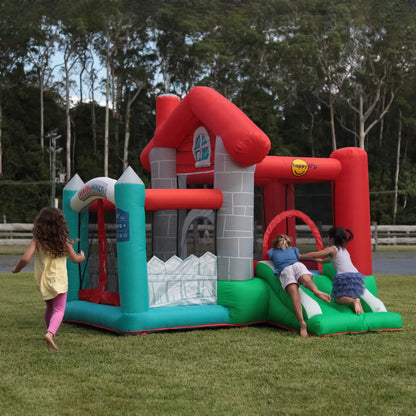 Colourful Happy Hop inflatable bouncy castle with integrated slide and enclosed ball pit set up on a green garden lawn during outdoor family play.