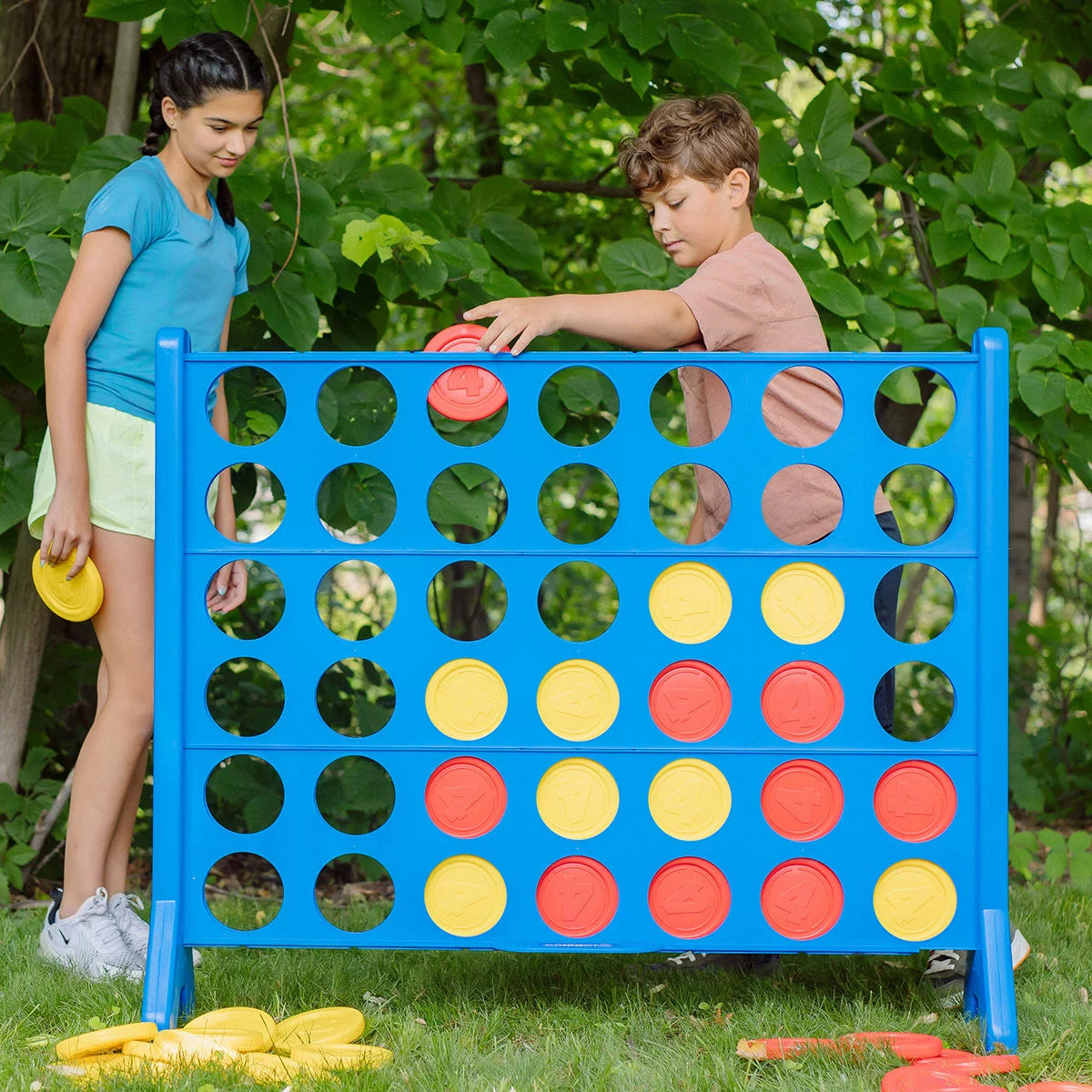 A life-sized Hasbro Giant Connect 4 game with red and yellow discs set up on a backyard lawn.
