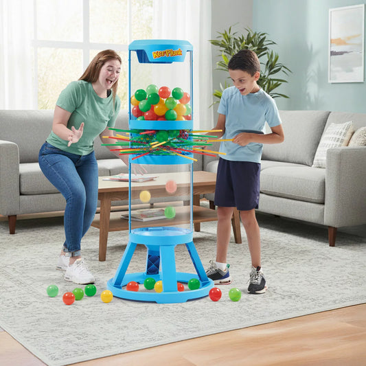 A life-sized Hasbro Giant KerPlunk game featuring a clear tower filled with colorful sticks and marbles on a lawn.