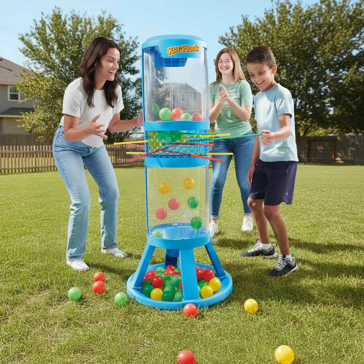 Hasbro Giant KerPlunk Game blue plastic tower standing 91cm tall on an outdoor green lawn with bright multicoloured sticks inserted through the frame holding large balls in place.