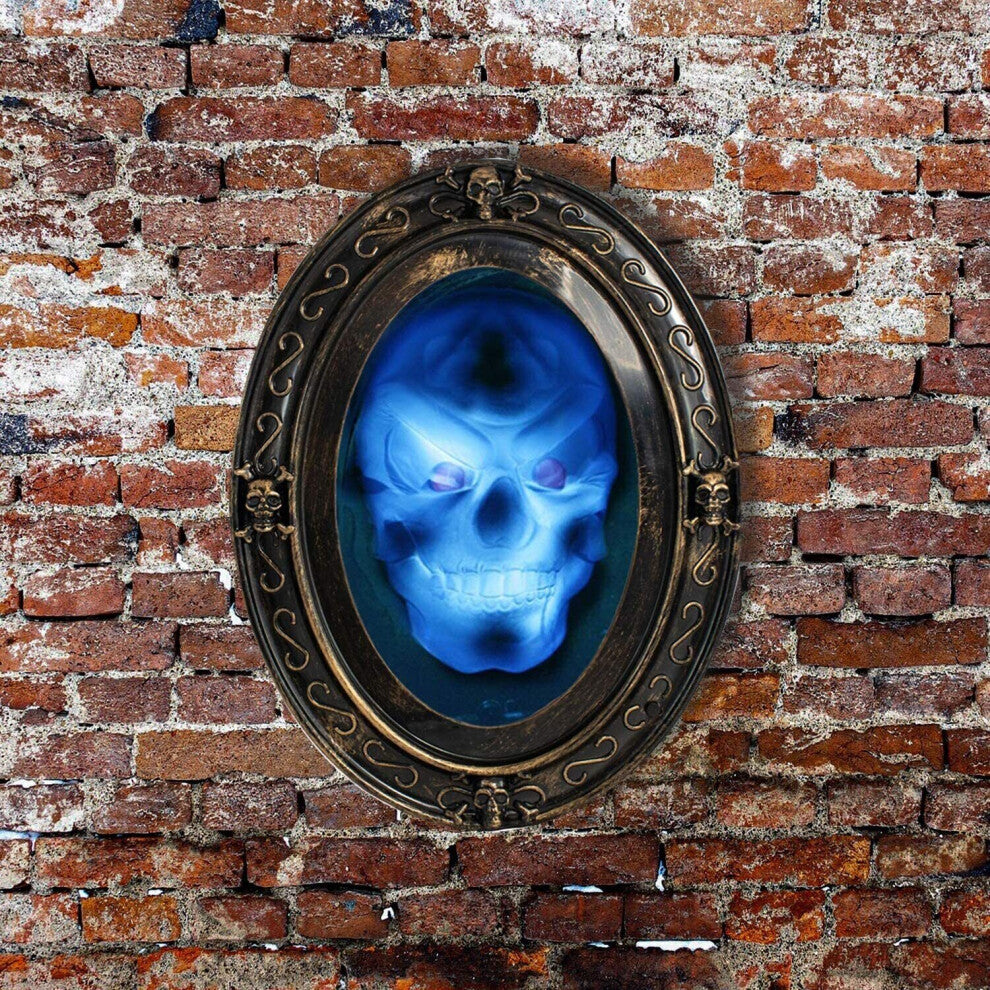 Front view of a vintage-style oval haunted mirror displaying a glowing flashing 3D skull face with red eyes in a dark room.