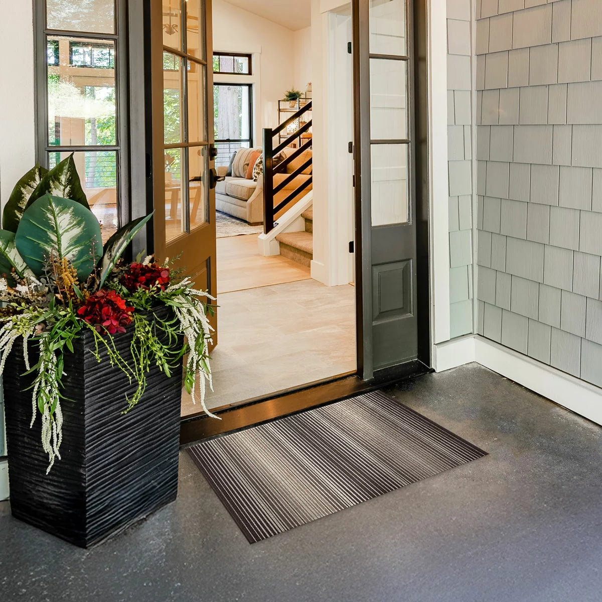 Top-down view of the black Korhani Loop Scraper Utility Mat showing its textured vinyl loop-scraper surface and low-profile edge on a modern wooden hallway floor.