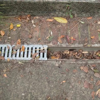 Black cylindrical polypropylene Hedgehog gutter brush guard displaying stiff radial bristles and wire central core laid inside a white plastic house gutter.