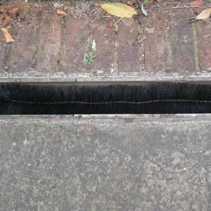 Black cylindrical polypropylene Hedgehog gutter brush guard displaying stiff radial bristles and wire central core laid inside a white plastic house gutter.