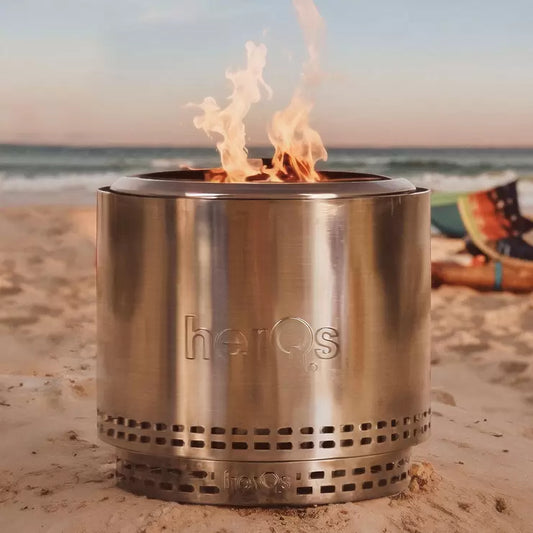 Modern HerQs Blaze 50cm stainless steel smokeless fire pit burning wood on a modern stone patio.