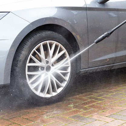 A Hilka 2,000W pressure washer set up on a residential driveway, with various attachments including the patio cleaner and foam bottle neatly arranged nearby.