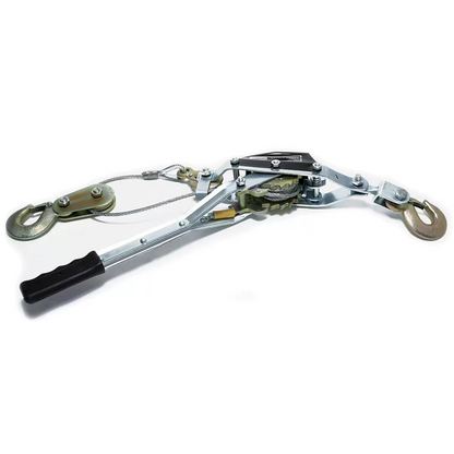 Heavy-duty steel Hilka Pro-Craft 800KG twin-ratchet power puller laying on grass next to an off-road vehicle tyre, showcasing its thick braided steel cable and three drop-forged steel hooks.