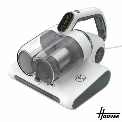 Front angle view of the compact grey Hoover 4-in-1 Mattress Vacuum Cleaner HMC510UV resting on a white quilted mattress surface, showcasing the LED display panel and roller brush base.