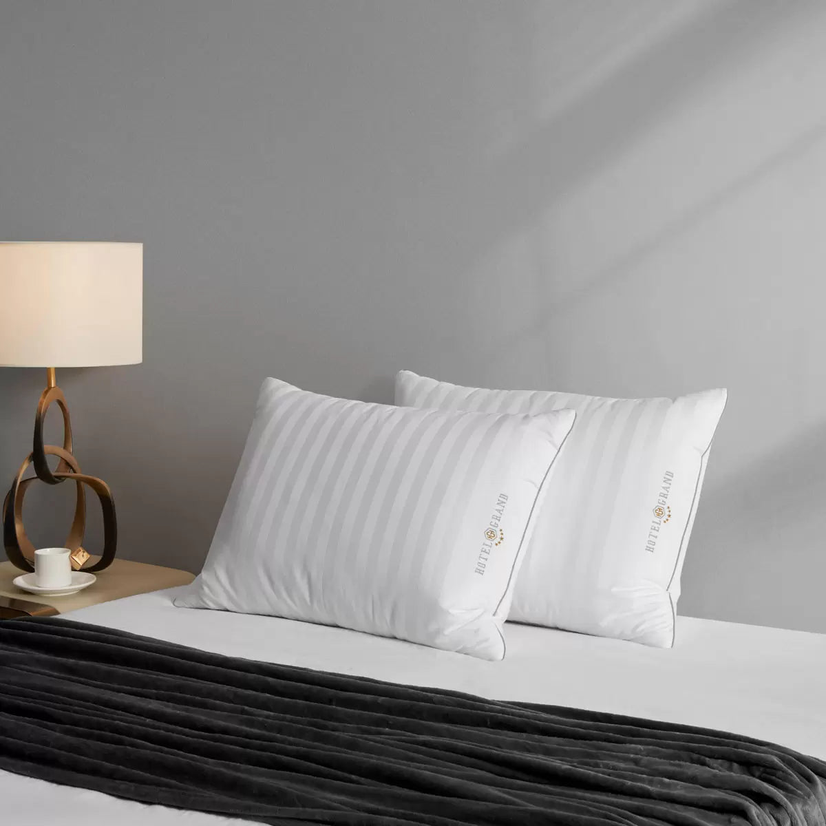 Hotel Grand Feather & Down Rolled Pillow 2 pack styled elegantly on a crisp white bed with silver piping details
