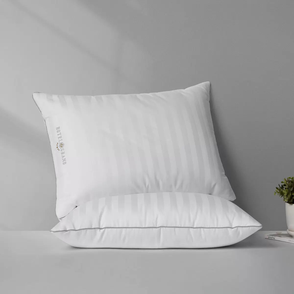 Hotel Grand Feather & Down Rolled Pillow 2 pack styled elegantly on a crisp white bed with silver piping details