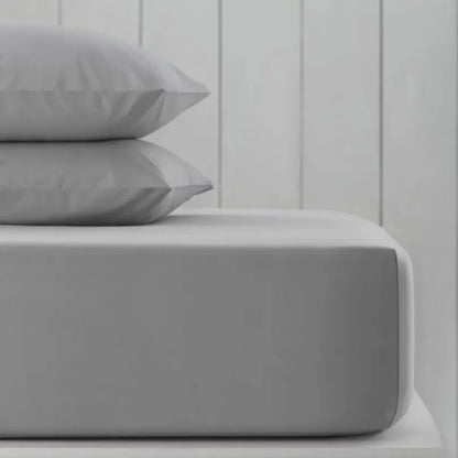 A pack of two neatly folded double-sized Hotel Signature cotton sateen fitted sheets showing the thick elastic corner grip on a clean bed.