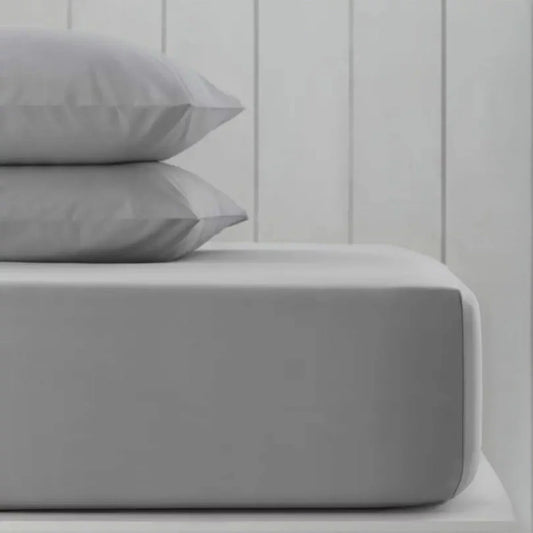 A pack of two neatly folded double-sized Hotel Signature cotton sateen fitted sheets showing the thick elastic corner grip on a clean bed.