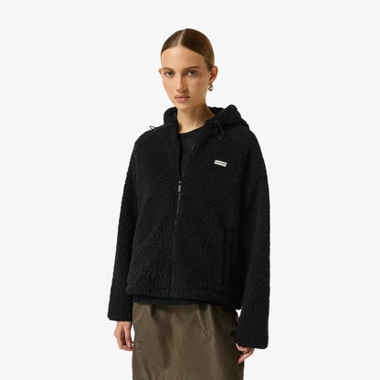 Side angle view of a woman wearing a beige Hunter Women's Highland Hooded Fleece with plush borg texture and a zip-up hood outdoors.