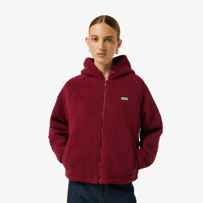 Side angle view of a woman wearing a beige Hunter Women's Highland Hooded Fleece with plush borg texture and a zip-up hood outdoors.
