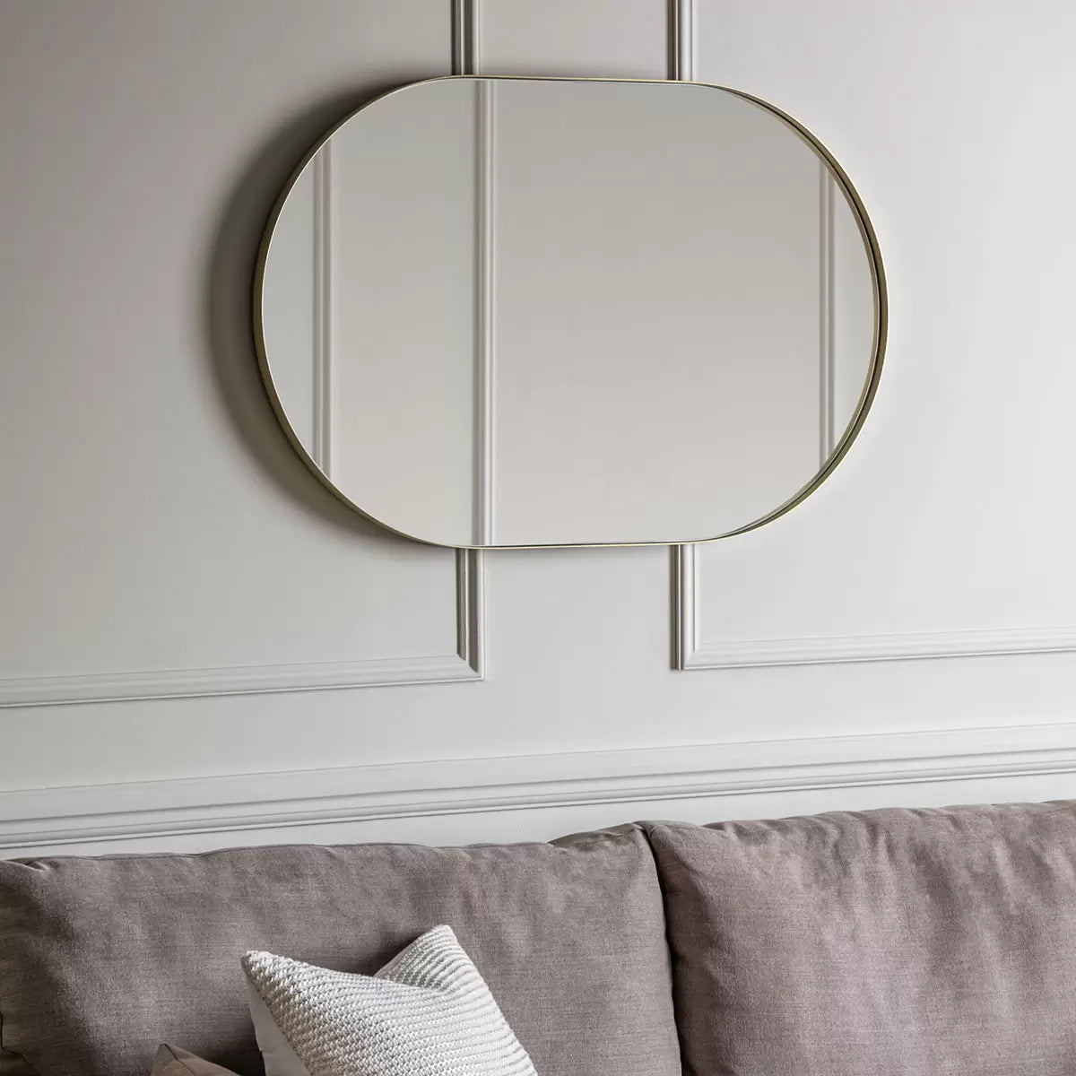 Gallery Hurston Elipse Champagne Mirror with smooth iron frame mounted vertically on a neutral living room wall
