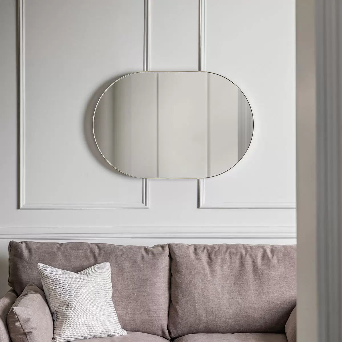 Gallery Hurston Elipse Champagne Mirror with smooth iron frame mounted vertically on a neutral living room wall