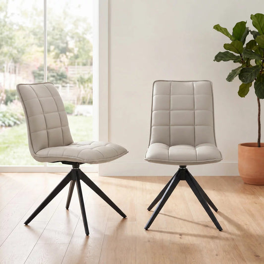 Pair of Indus Valley Skylar taupe faux leather dining chairs with quilted square stitching and black metal 360-degree swivel spider legs.
