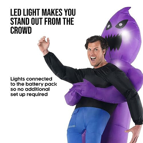 Front view of an adult wearing a purple inflatable carrying ghoul costume with an illuminated LED face glowing in a dimly lit setting.