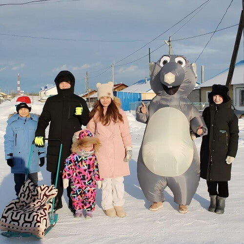 Full-length front view of an adult wearing an inflated grey cartoon mouse costume with big round ears standing in a brightly lit room.