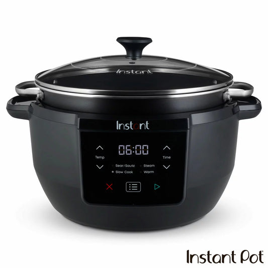 A black Instant Pot Superior 7.1L slow cooker sitting on a wooden kitchen surface with its glass lid resting neatly on top.