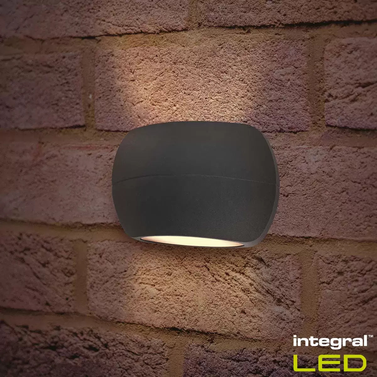 Two black Integral Luxstone up-and-down wall lights mounted on a modern brick wall, casting beams of light vertically.