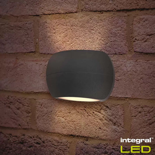 Two black Integral Luxstone up-and-down wall lights mounted on a modern brick wall, casting beams of light vertically.