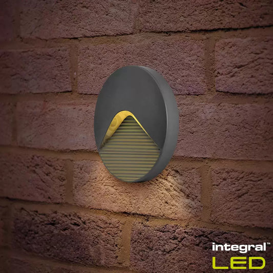 Two Integral Pathlux step lights mounted low on a stone garden wall, casting a soft pool of light onto dark stone stairs.